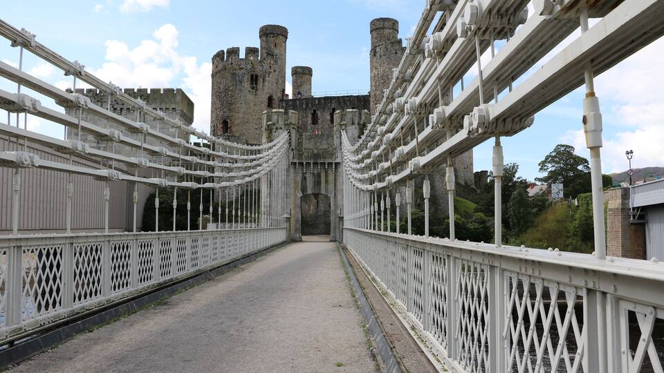 A bridge with white railings and a castle in the background.