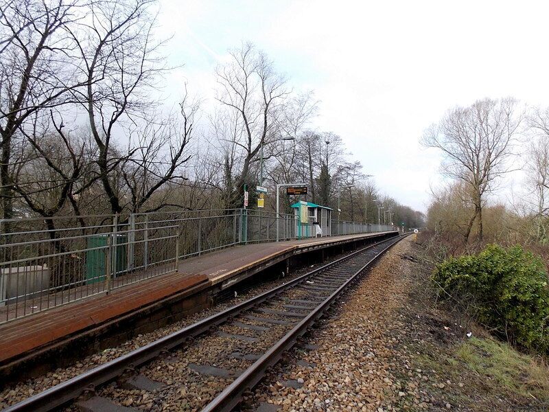 A railway platform with a signal box and tracks surrounded by leafless trees.