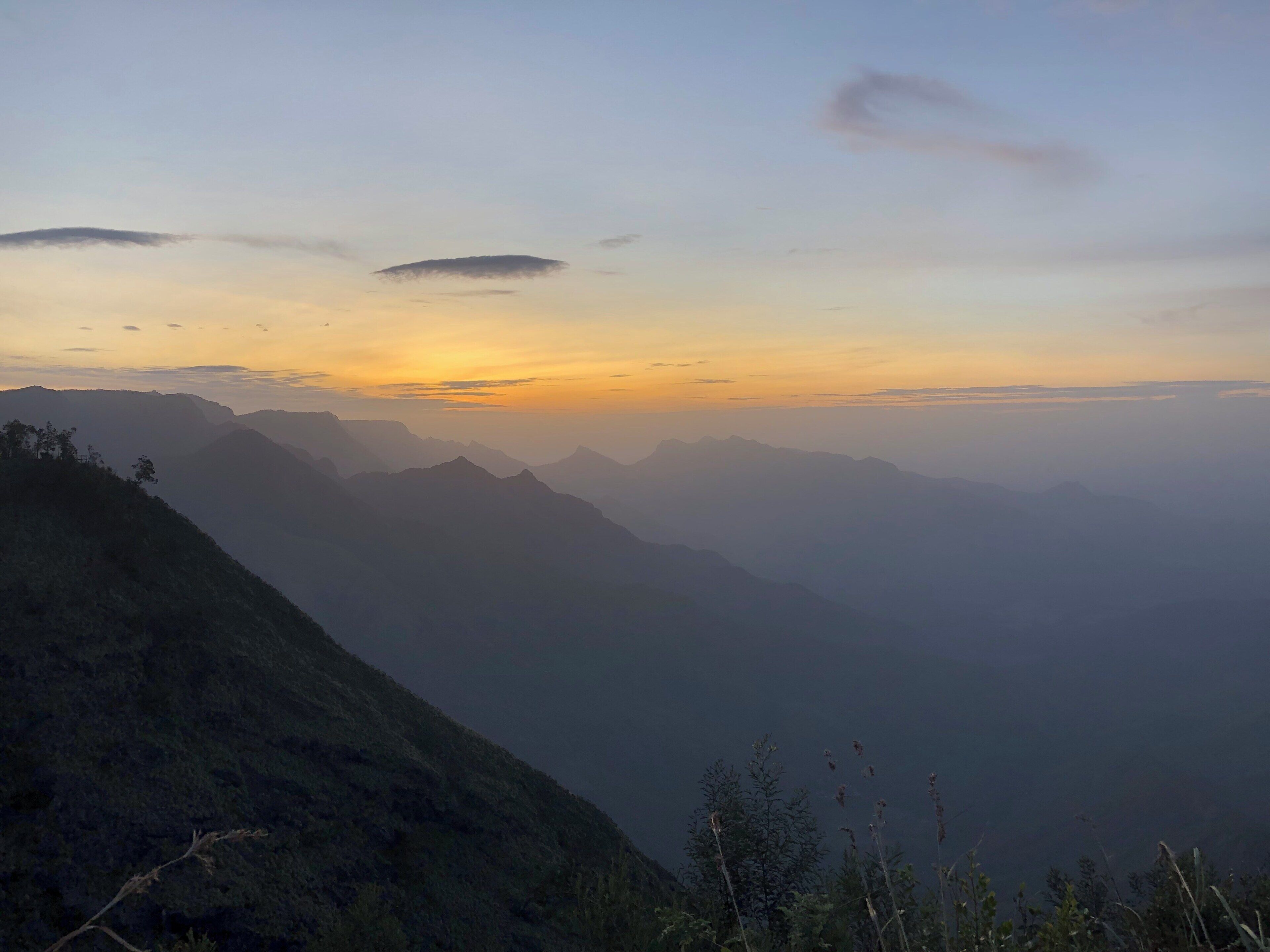 A mountain range at sunrise with mist-covered peaks and a clear sky.