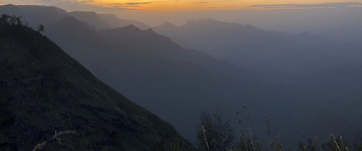 A mountain range at sunrise with mist-covered peaks and a clear sky.