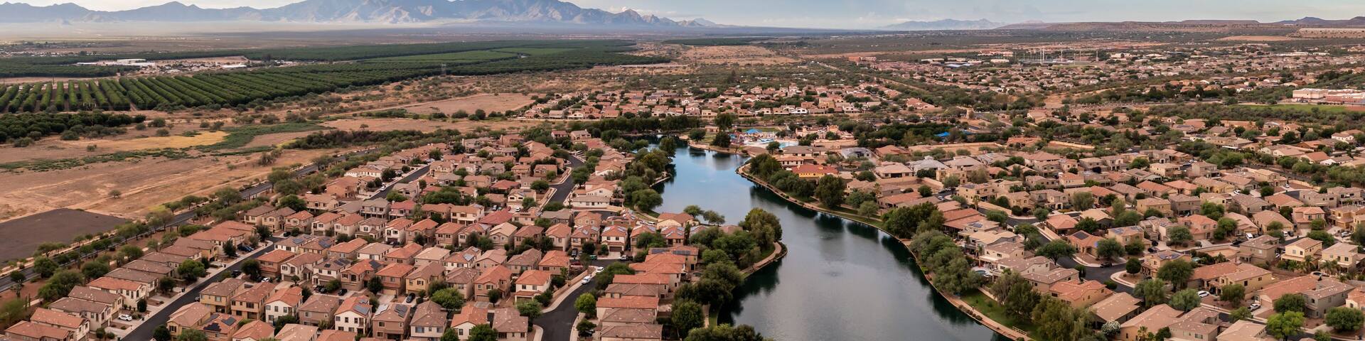 A river winding through a residential area with mountains in the background.