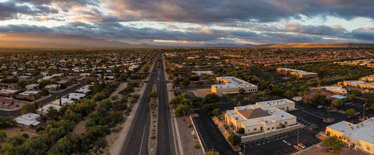 An aerial view of a suburban area with a main road, residential houses, and a large building complex.