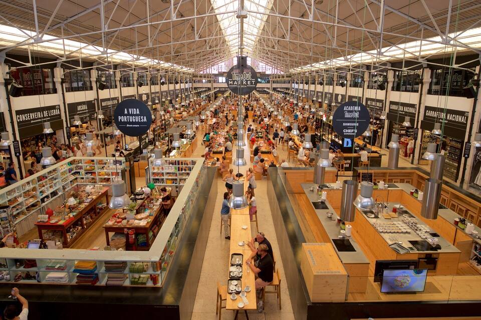 Mercado interno movimentado com vários quiosques de comida e compradores.