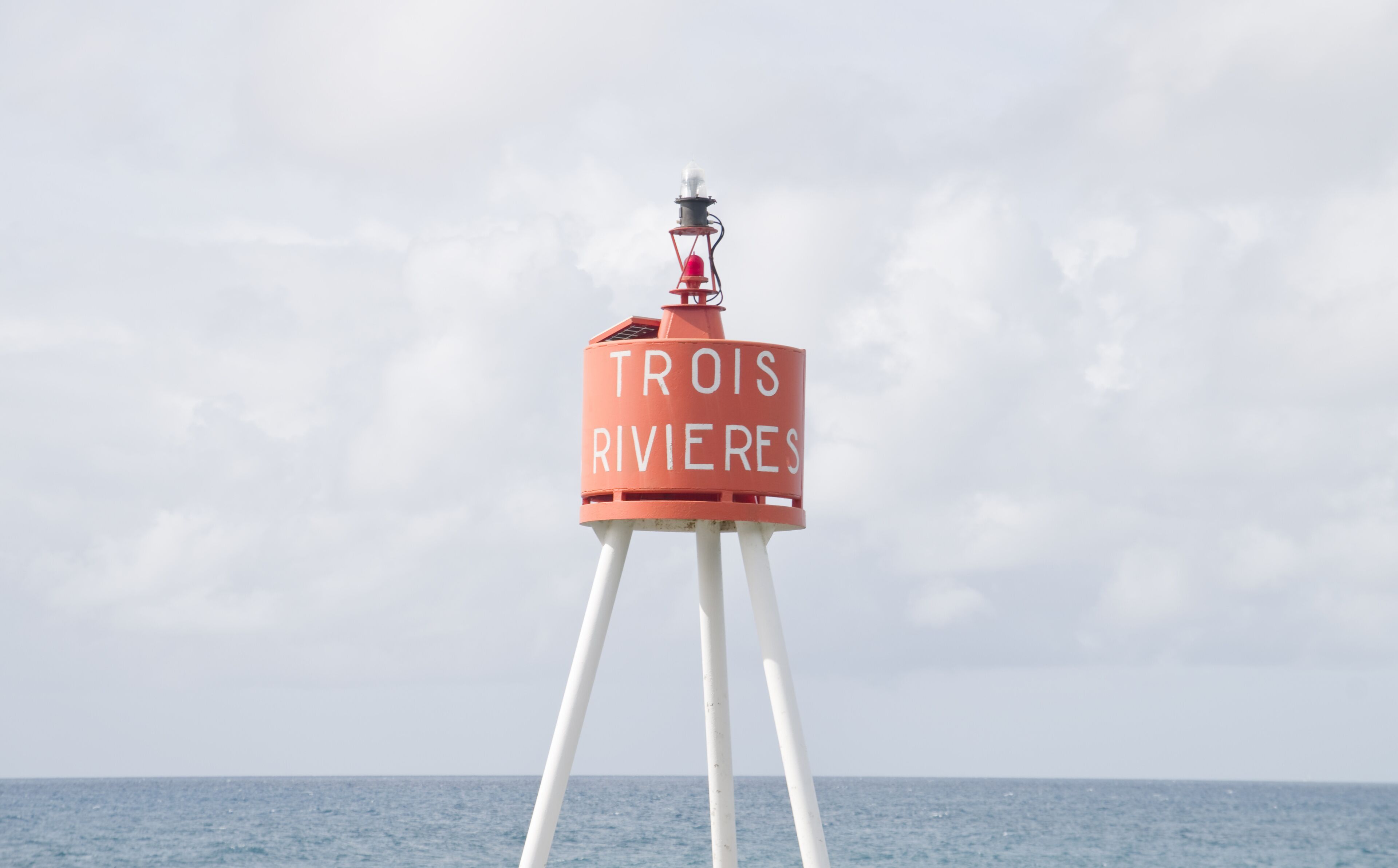 A buoy with the text "TROIS RIVIERES" in the ocean.