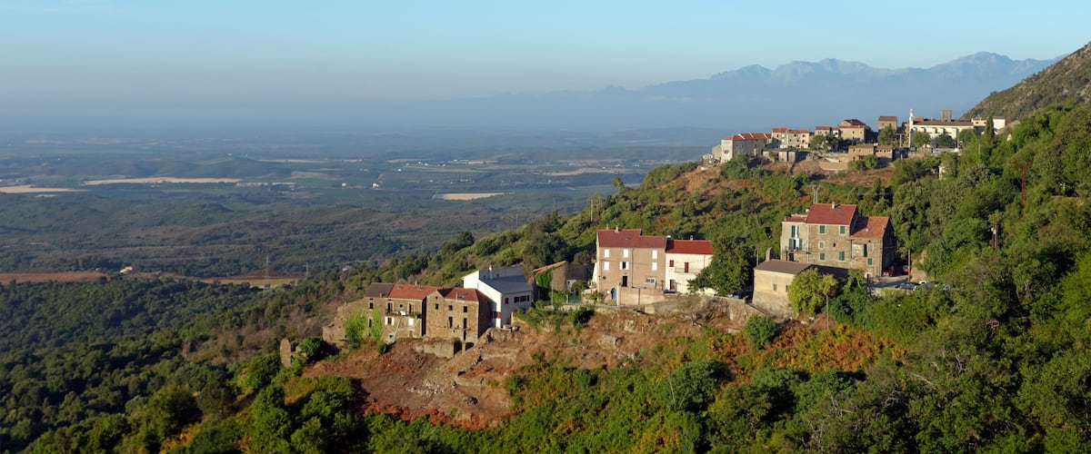 A hillside village with traditional stone buildings and a view of the valley below.