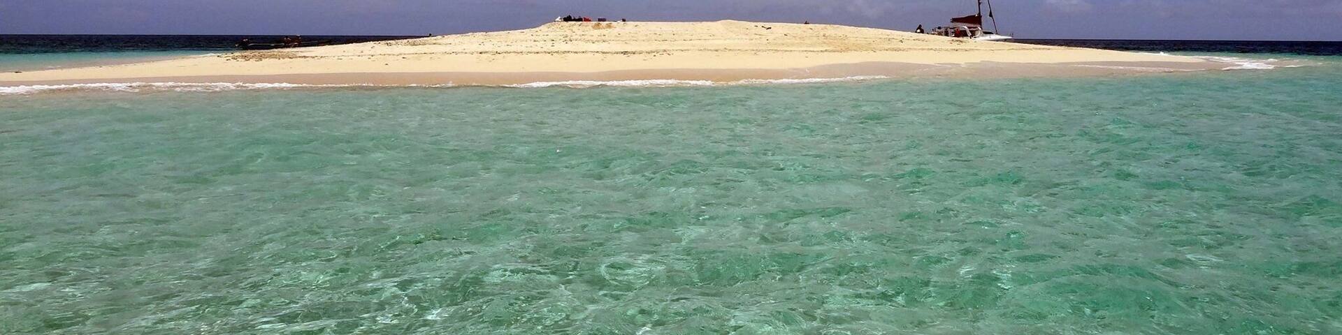 A beach with clear turquoise water and a sandy shore.