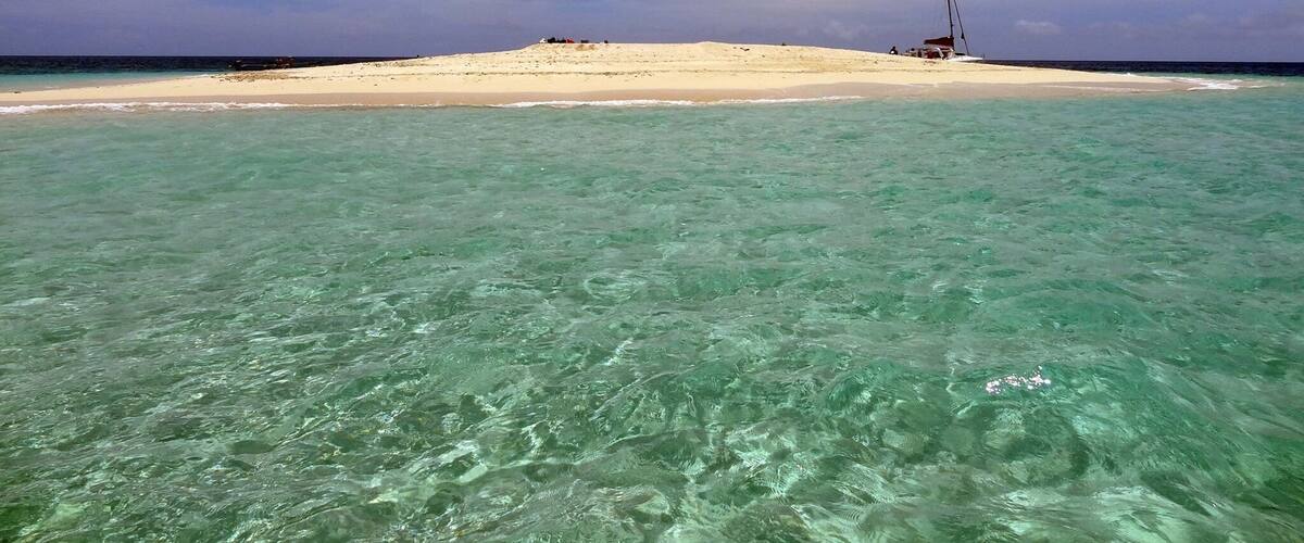 A beach with clear turquoise water and a sandy shore.