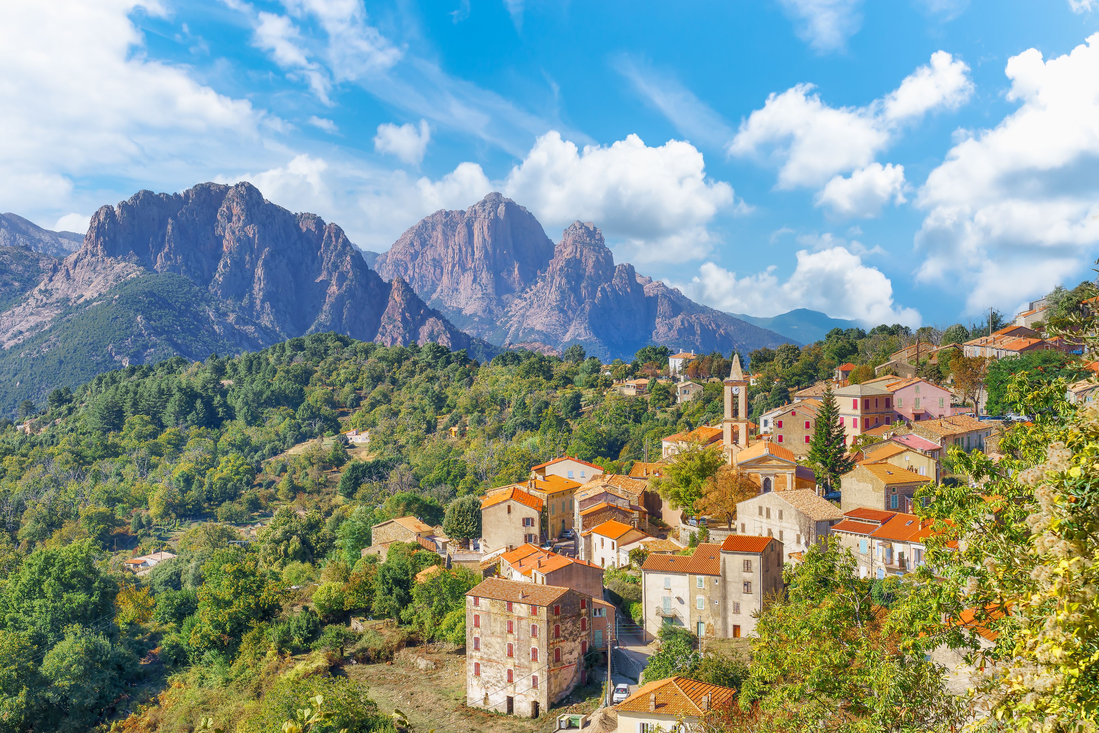 A mountainous village with terracotta-roofed buildings nestled among lush greenery.