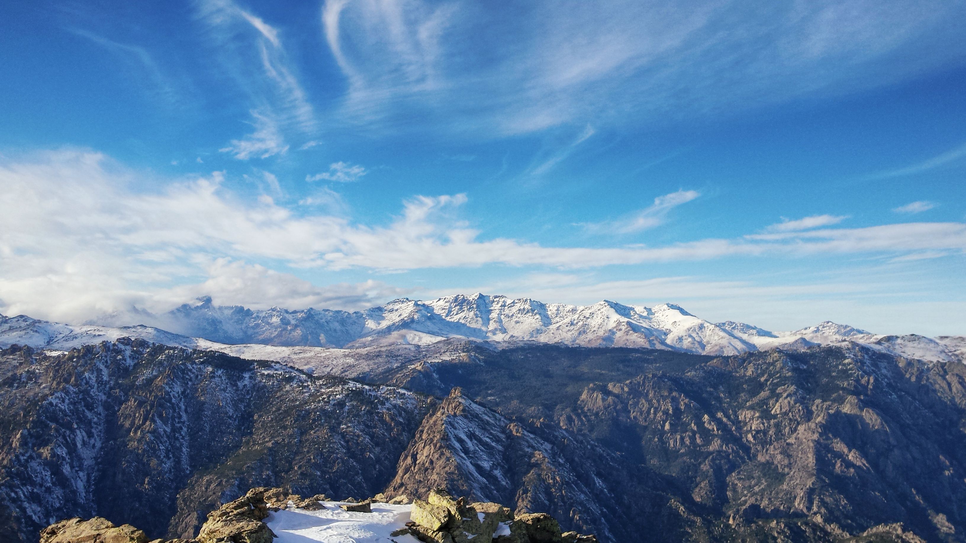 A mountain range with snow-capped peaks under a clear blue sky.