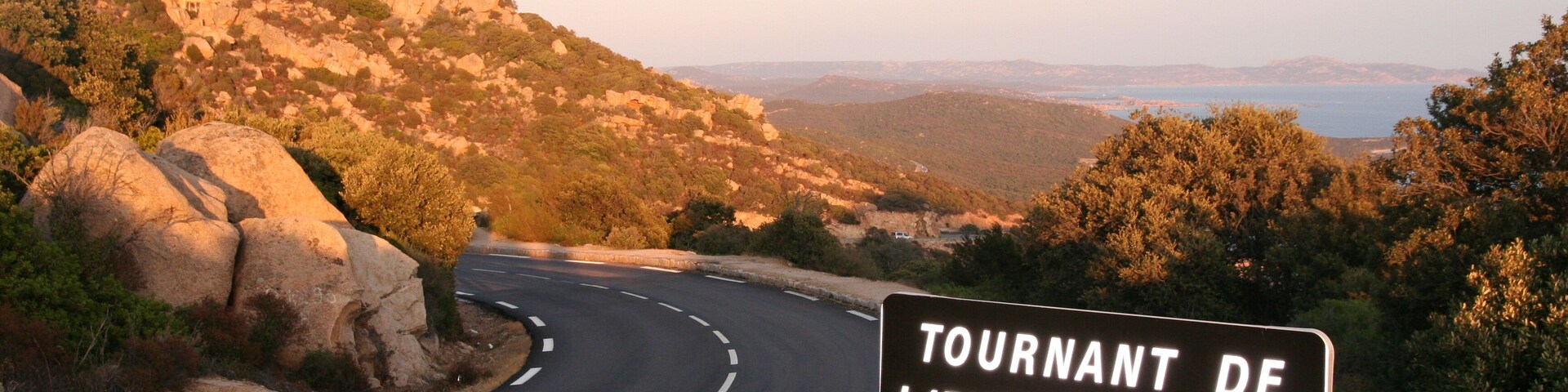Un camino sinuoso con un cartel que indica Tournant de L'Extrême-Sud, una ruta panorámica en el territorio de Monacia d'Aullene.