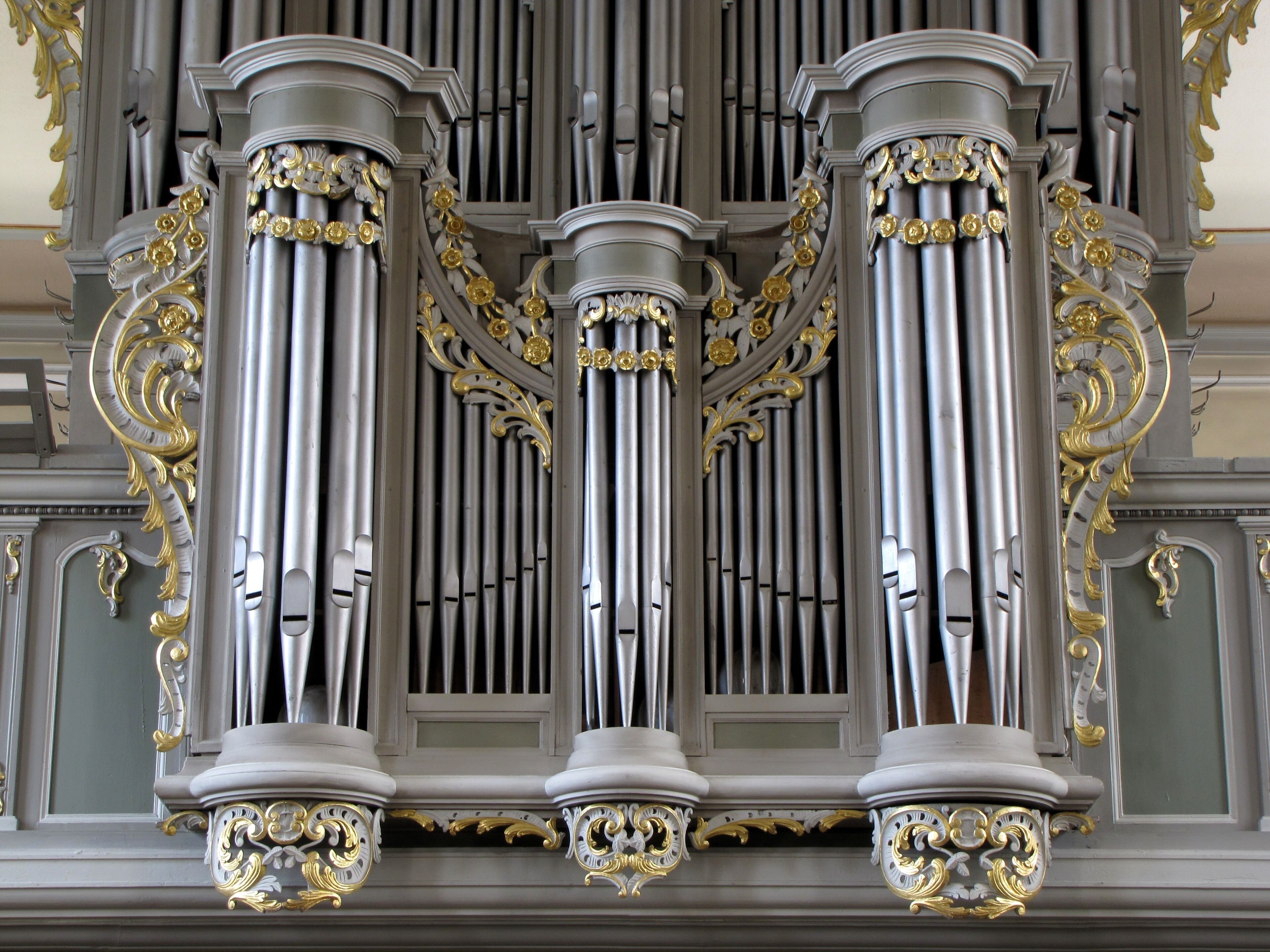 An ornate organ with three large columns and intricate gold detailing.