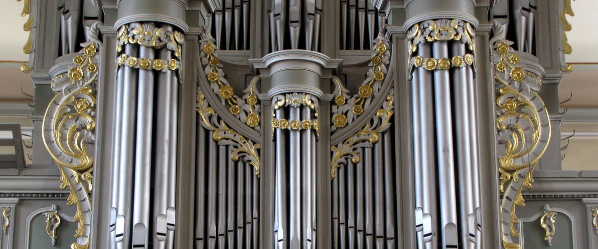 An ornate organ with three large columns and intricate gold detailing.