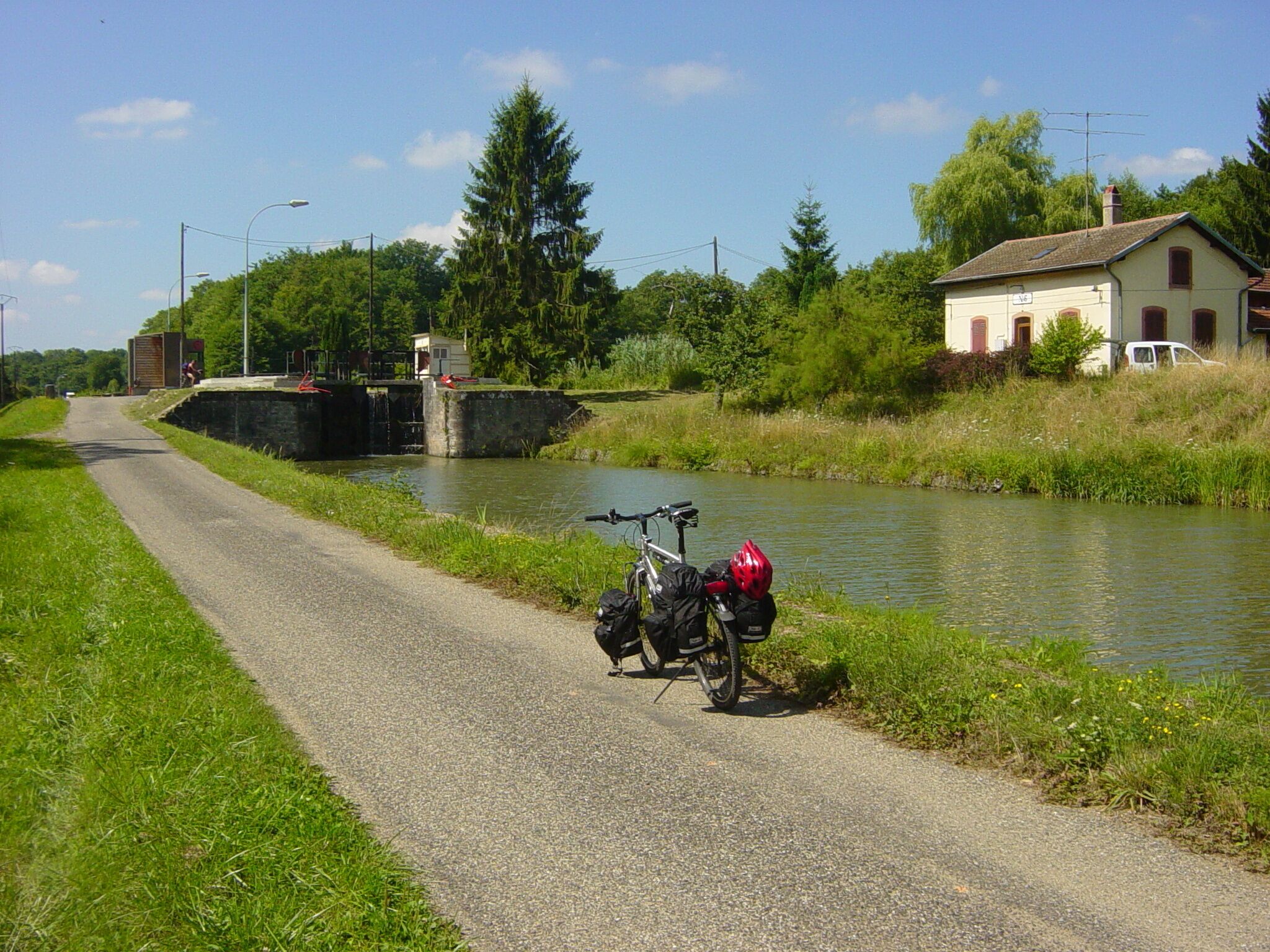 A narrow road alongside a canal with a bicycle parked on the side.