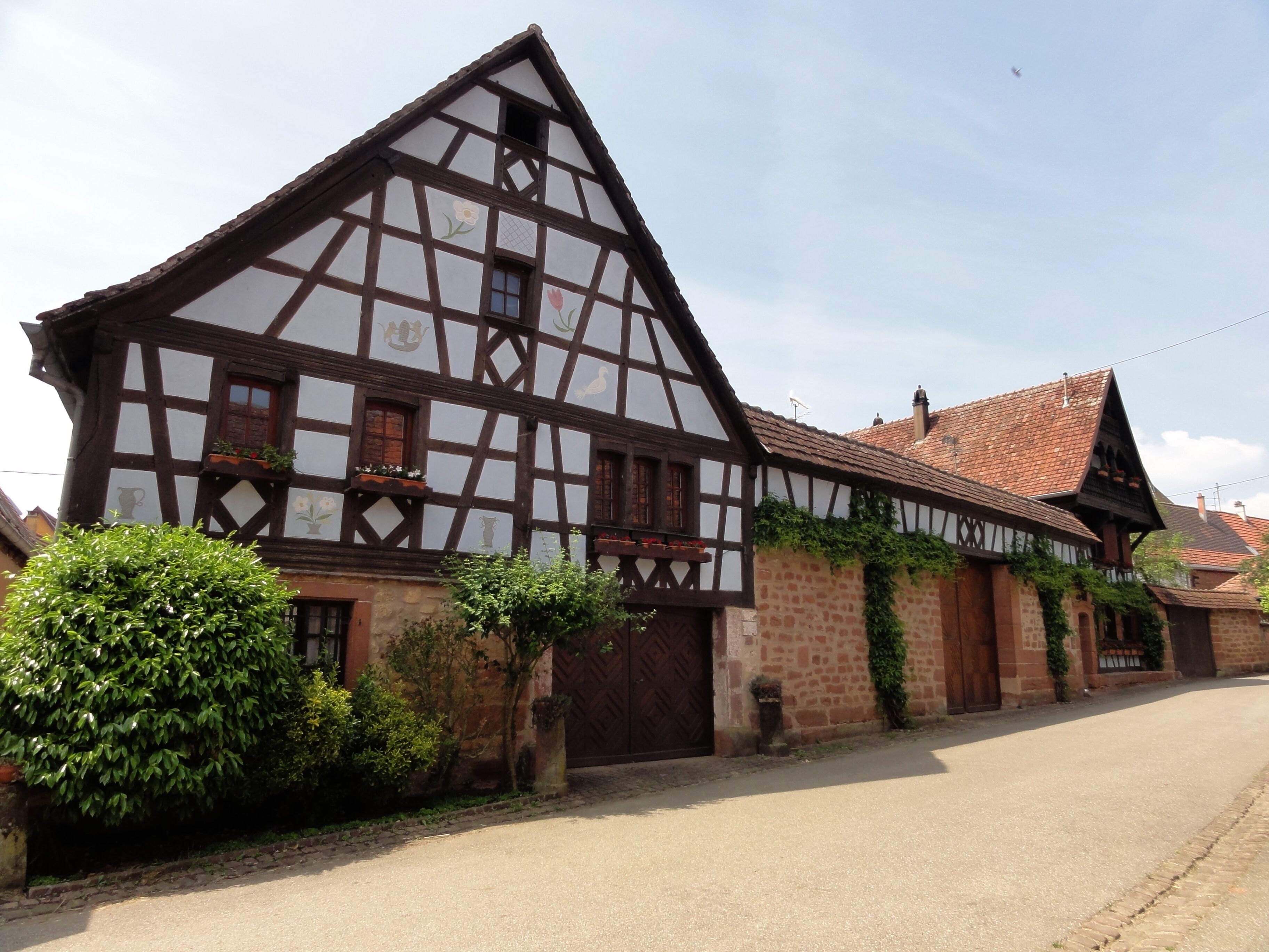 A traditional half-timbered house with a sloped roof and a large wooden door.