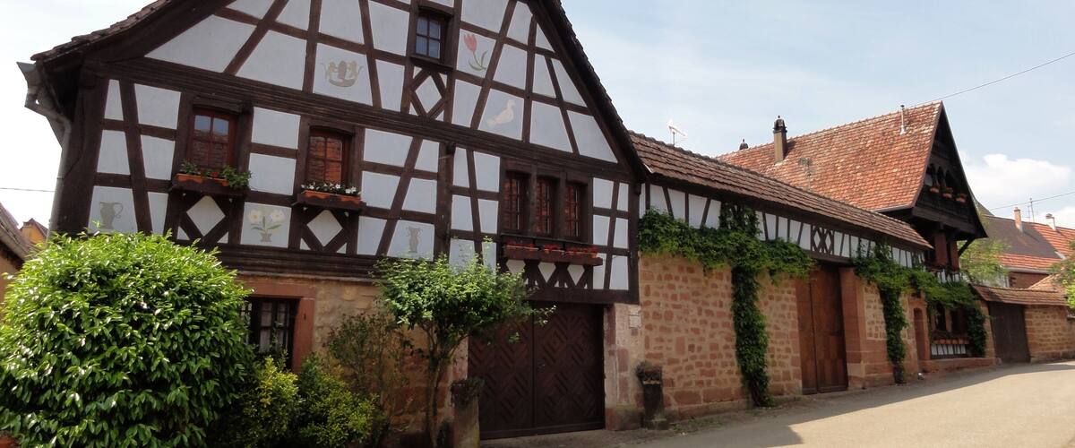 A traditional half-timbered house with a sloped roof and a large wooden door.