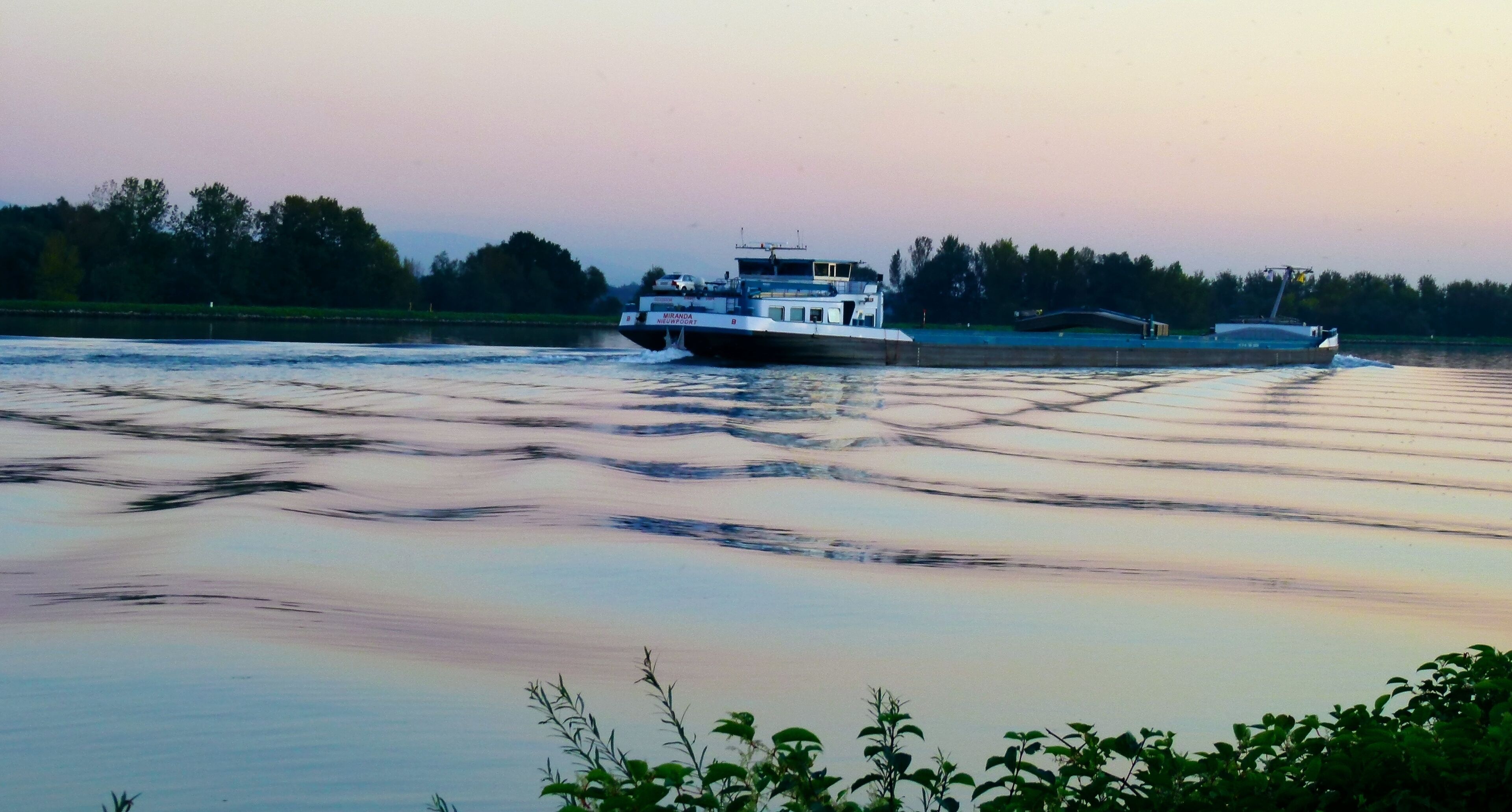 A river with a boat named 'Miranda' moving across the water.