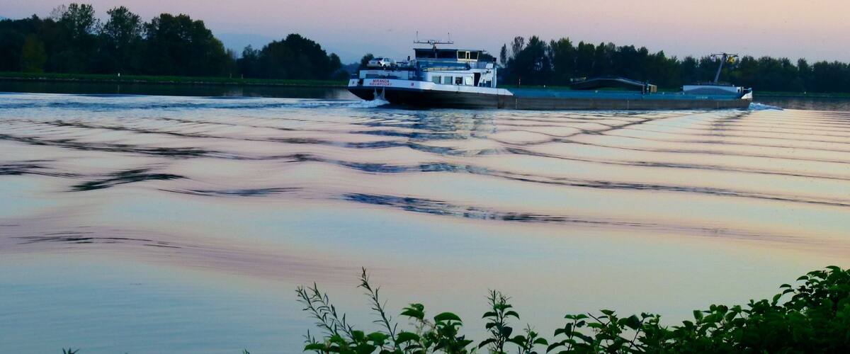 A river with a boat named 'Miranda' moving across the water.