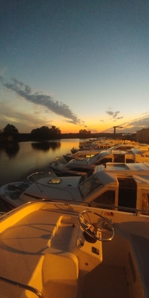 A marina with several boats docked during sunset.