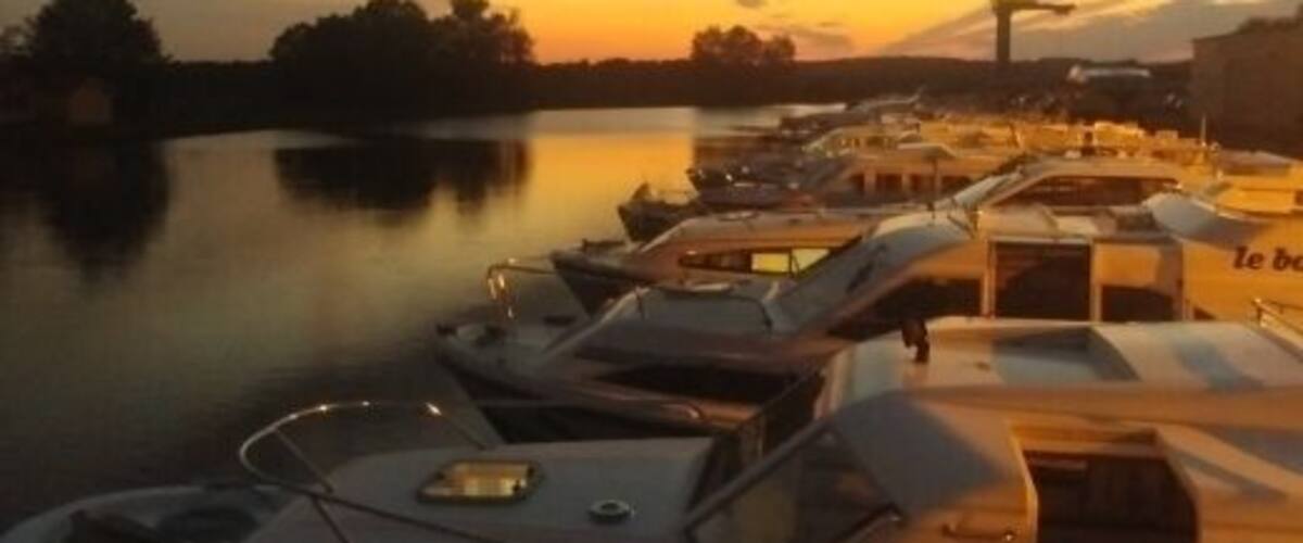 A marina with several boats docked during sunset.