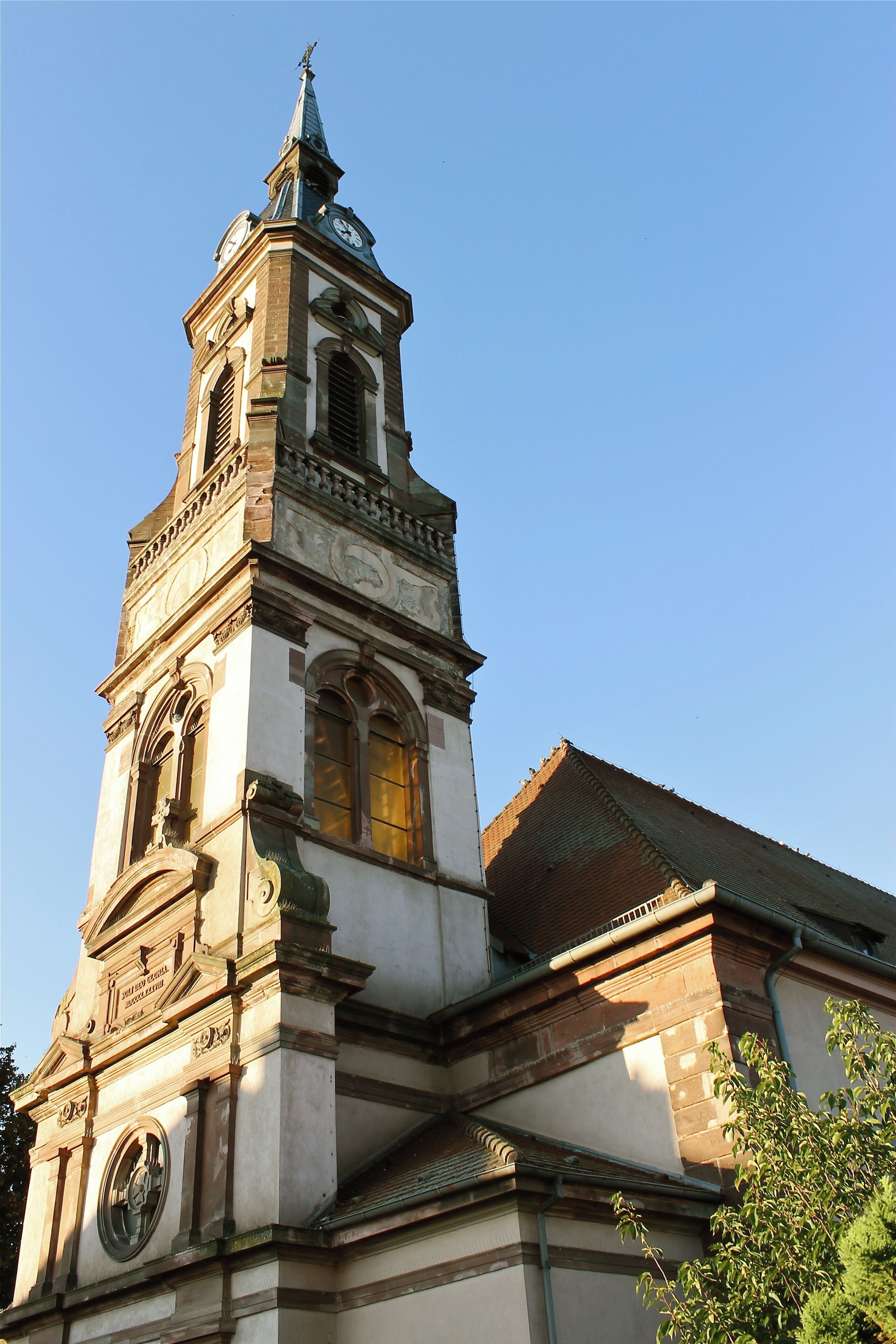 A church with a tall bell tower, arched windows, and a clock.