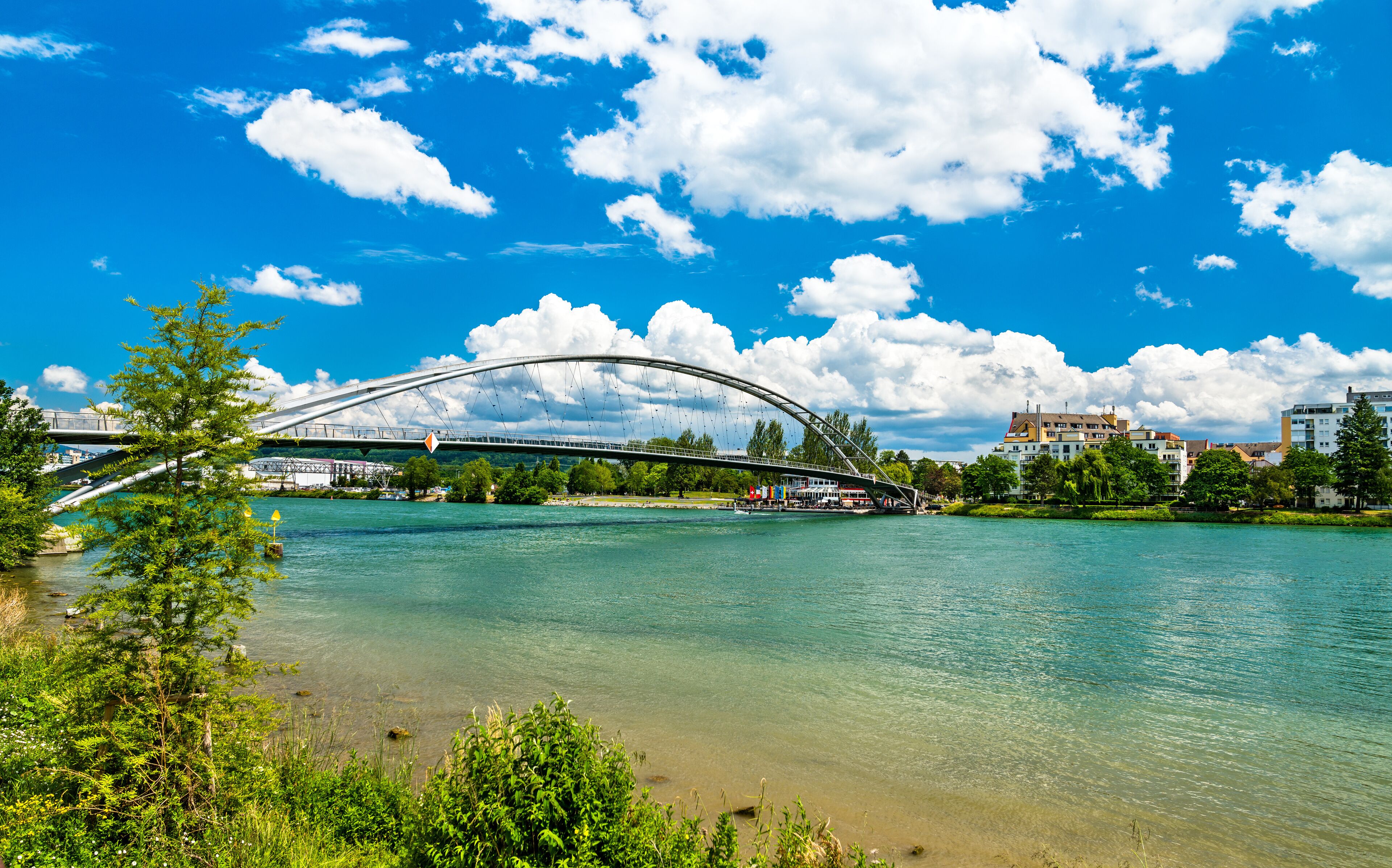 A river with a bridge, trees, and buildings in the background.