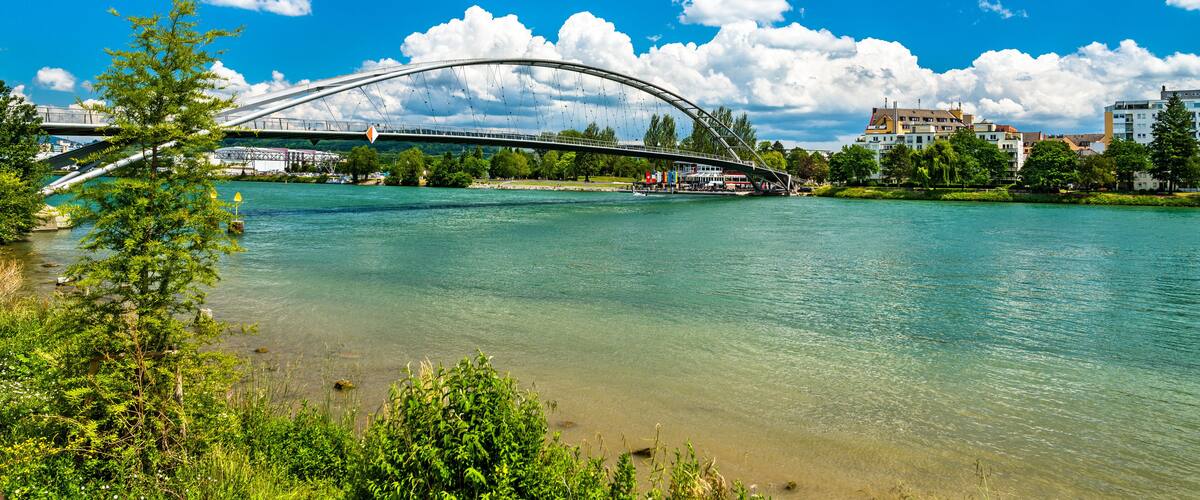 A river with a bridge, trees, and buildings in the background.