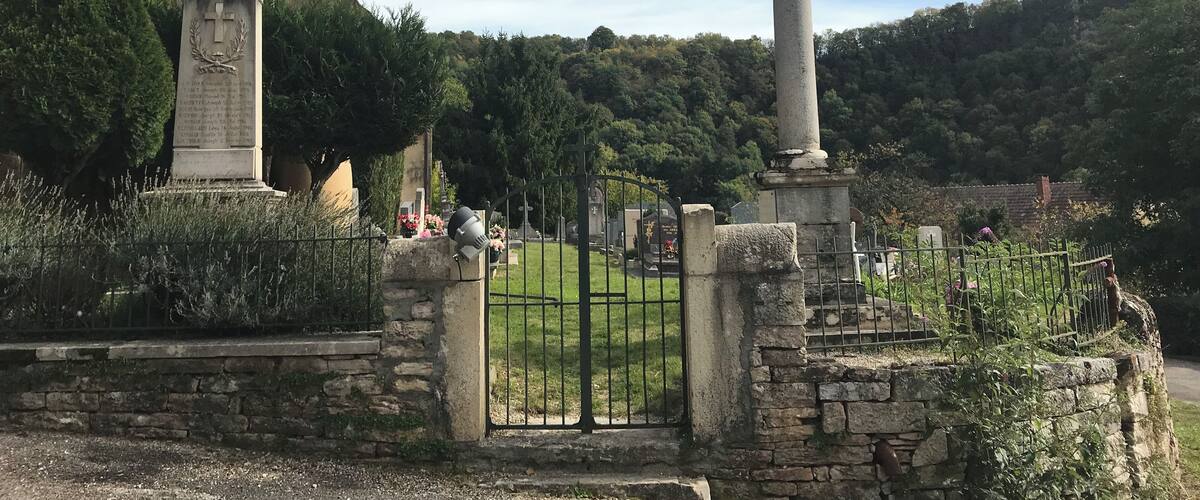 A church with a tall cross, a stone monument, and a cemetery.