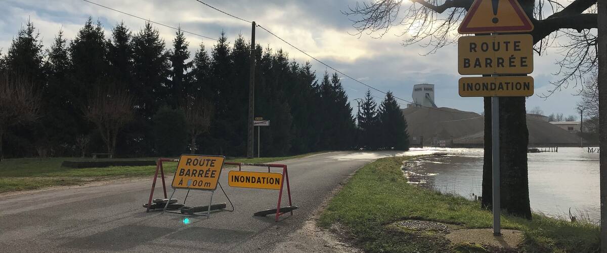 A road closure with signs indicating 'Route Barrée' and 'Inondation'.