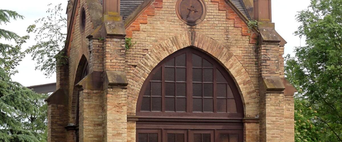 A historic church with a tall steeple, a large arched entrance, and a clock.