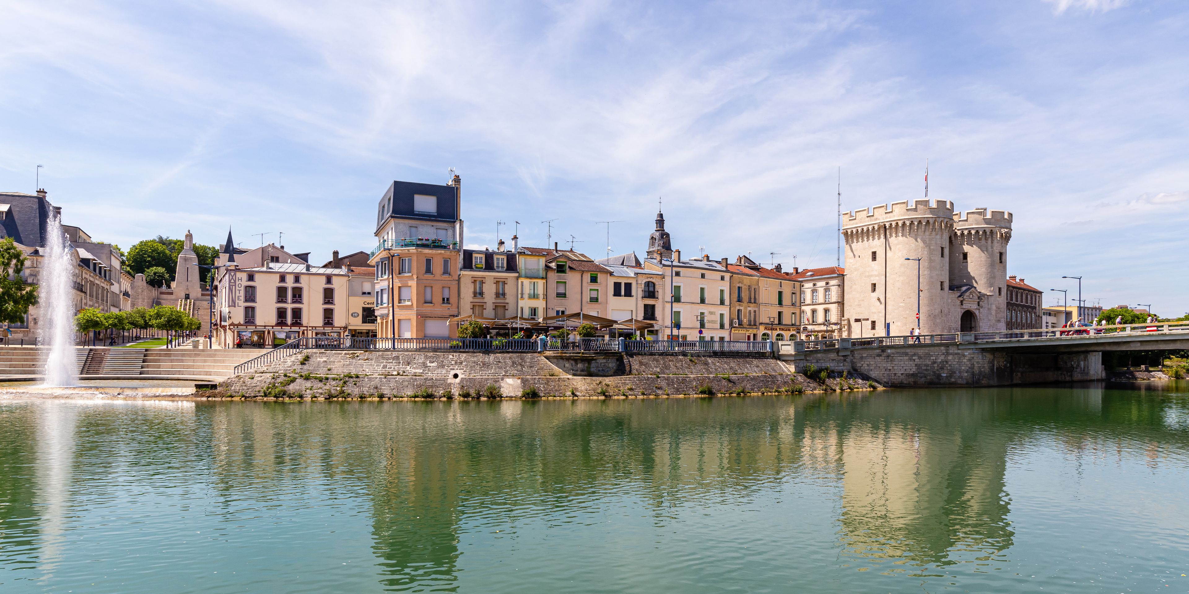 A historic town with a castle, a river, and a fountain.