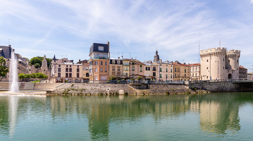 A historic town with a castle, a river, and a fountain.