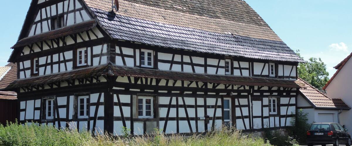 A traditional half-timbered house with a steeply pitched roof and a chimney.