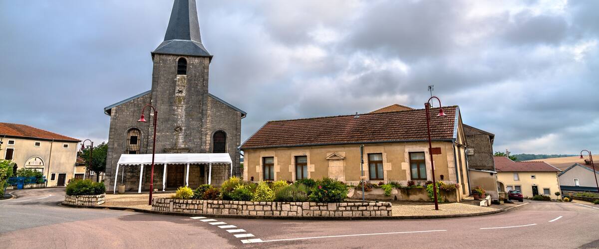 A church with a tall steeple, a small white building with a red roof, and a road with a white dashed line.