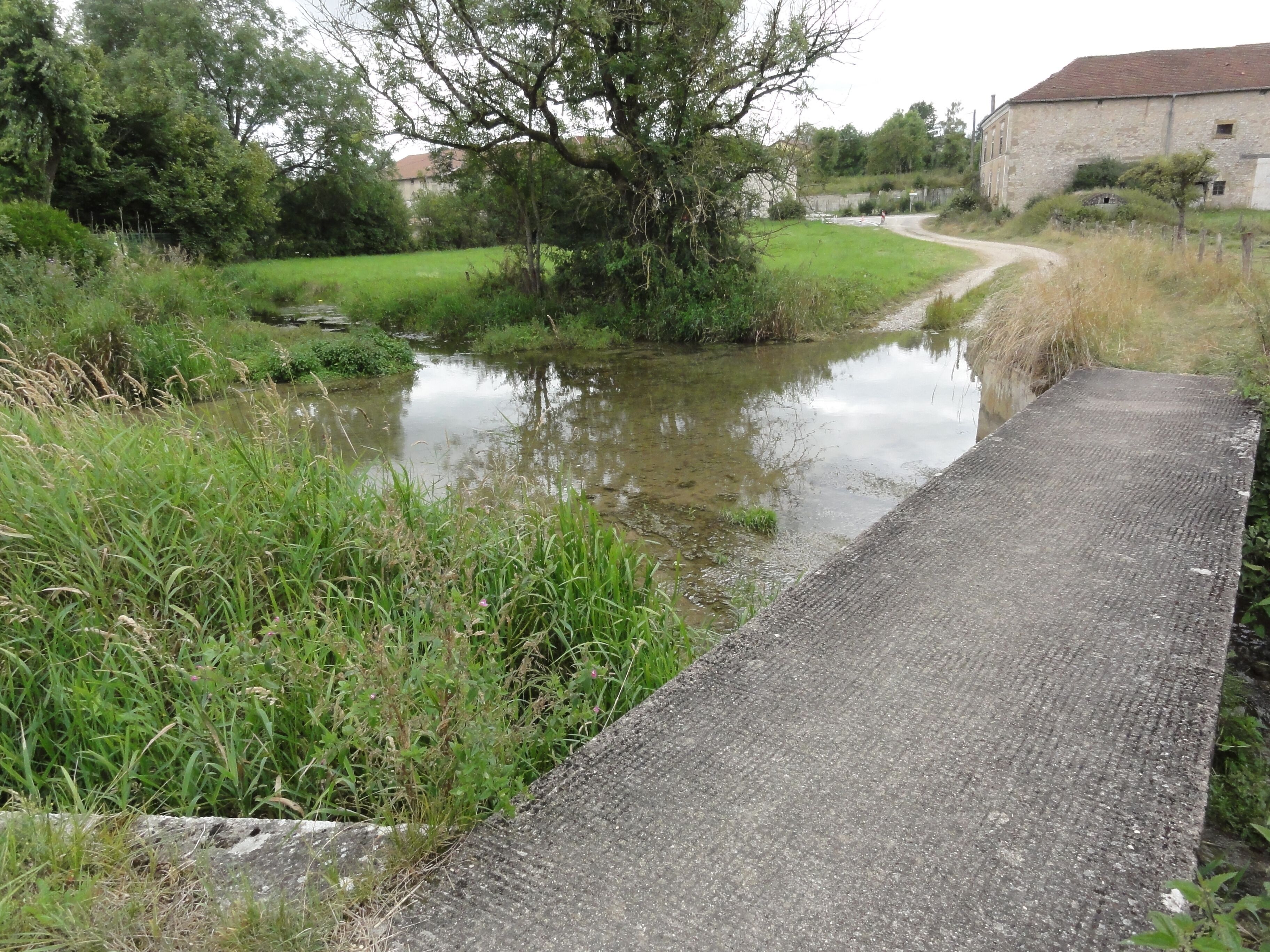 A narrow waterway with a concrete pathway alongside.