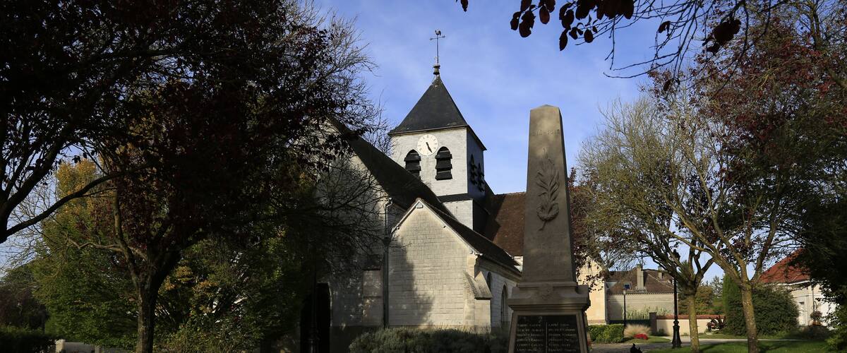 A church with a clock tower, surrounded by trees and a gravestone.