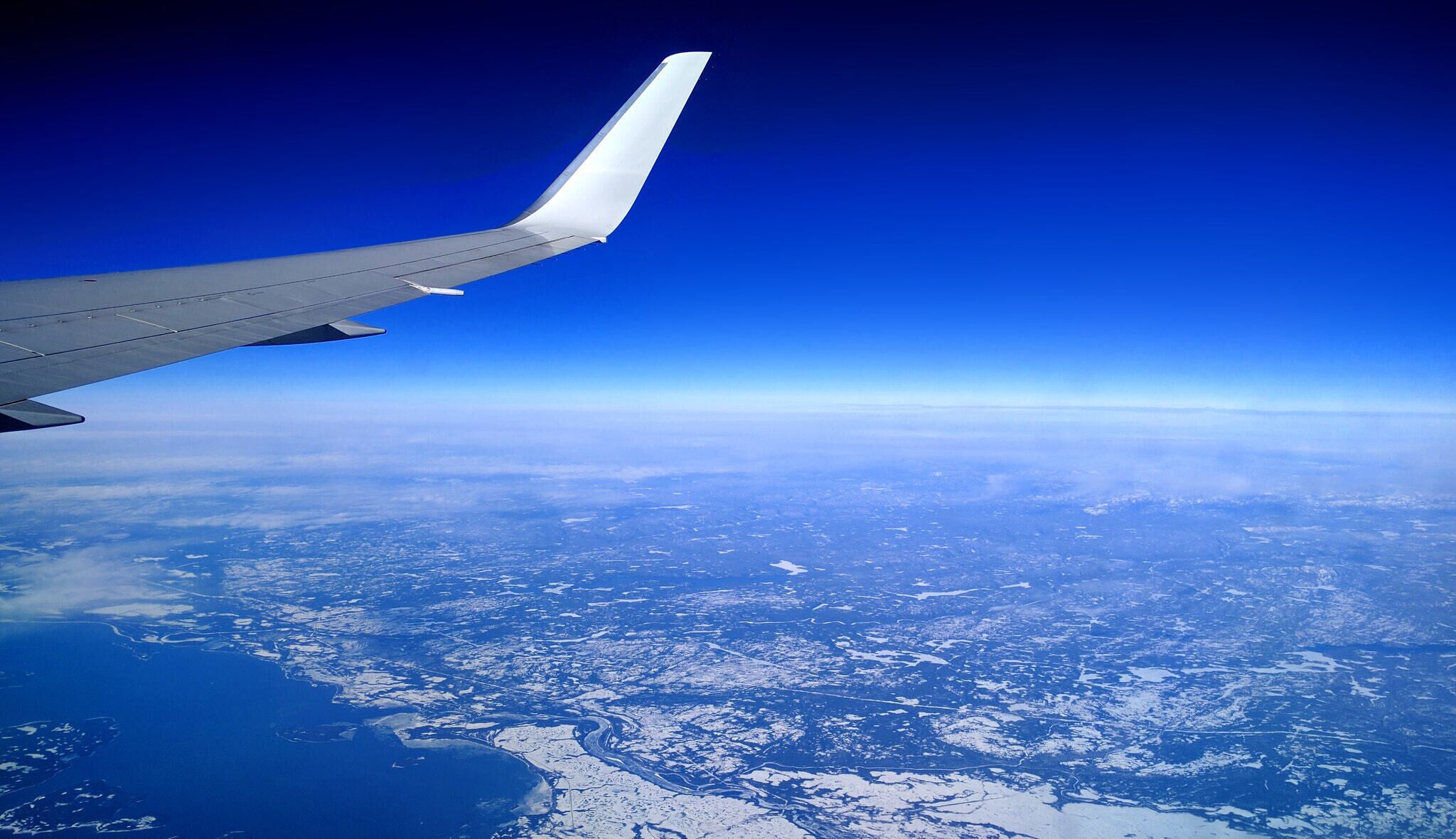 An airplane wing with a clear view of a snowy landscape below.
