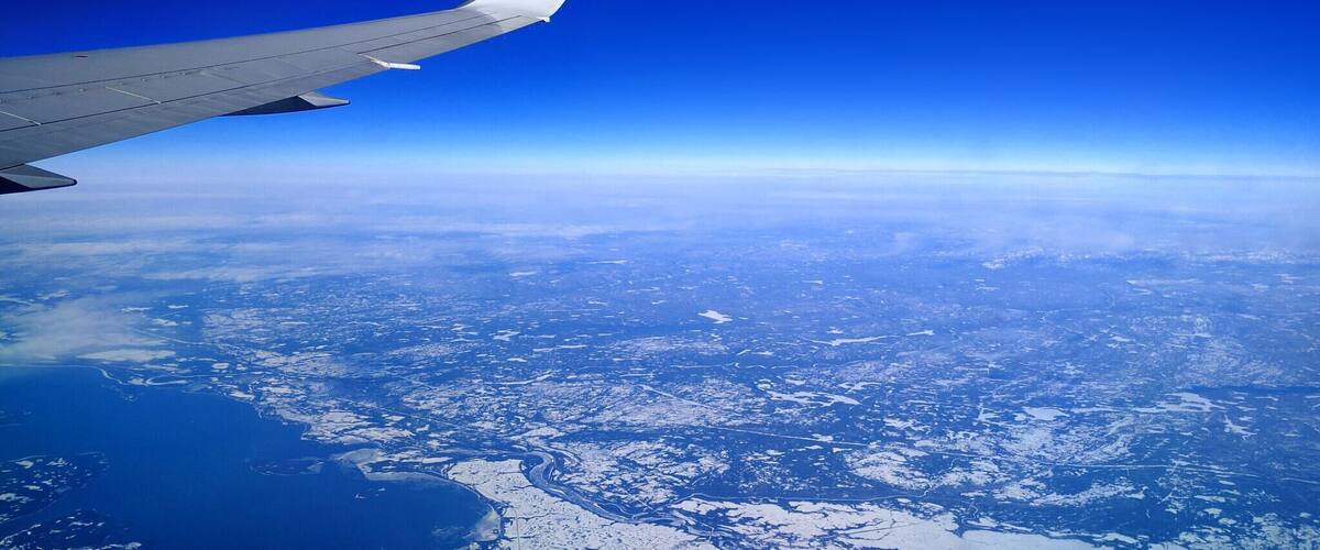 An airplane wing with a clear view of a snowy landscape below.