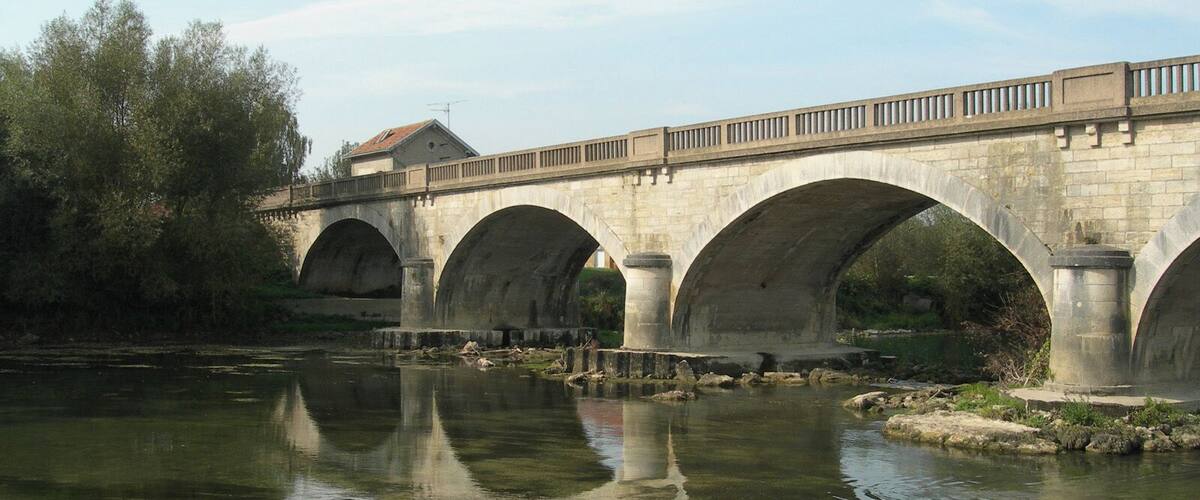A stone bridge with multiple arches over a calm river.