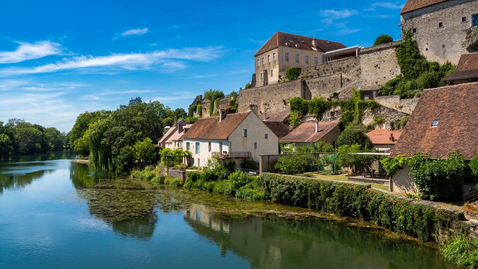 A river with houses and a castle on a hill.