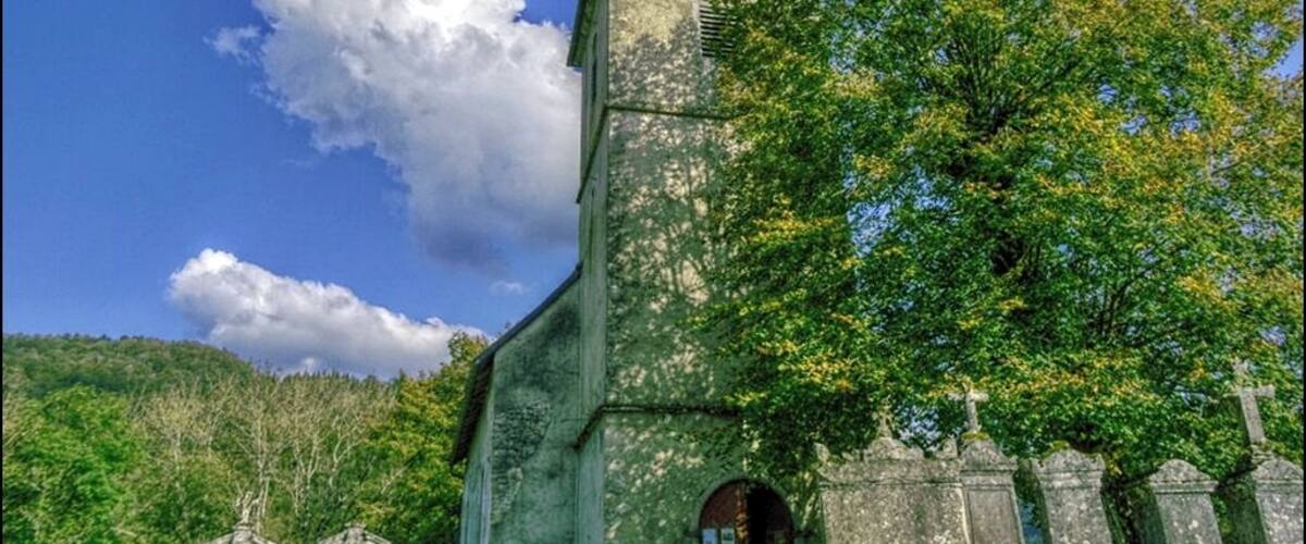 A church with a cross on the roof, surrounded by trees and a clear sky.