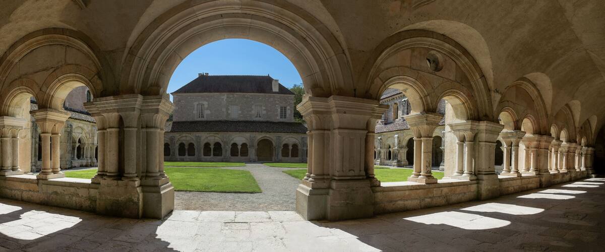An ancient cloister with stone arches and a courtyard.