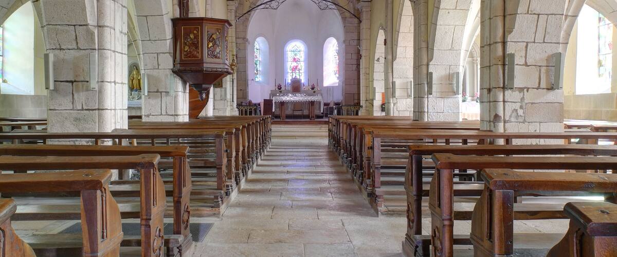 A church interior with arched ceilings, wooden pews, and a central altar.