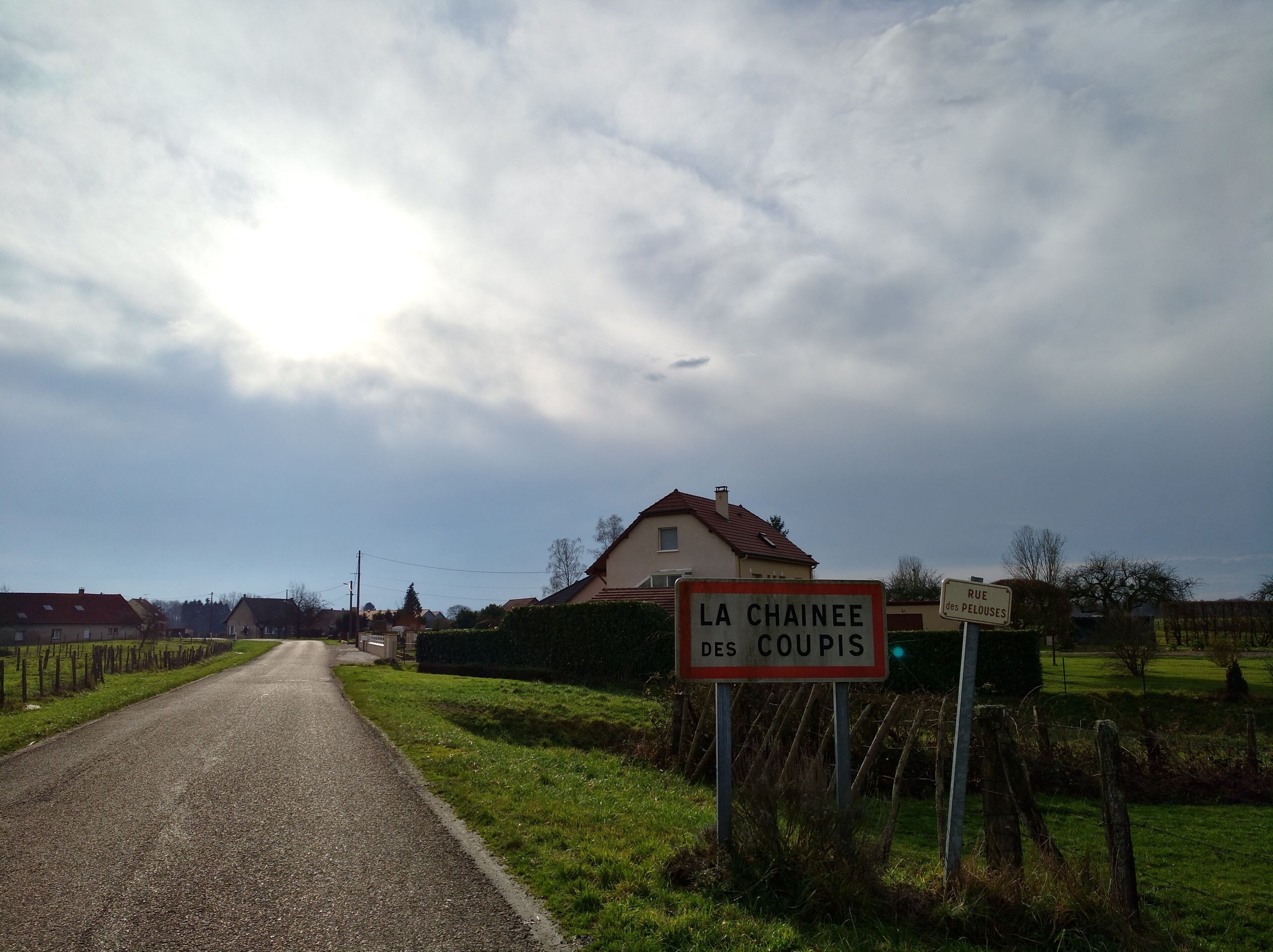 A rural road with a sign reading "La Chainee des Coupis".