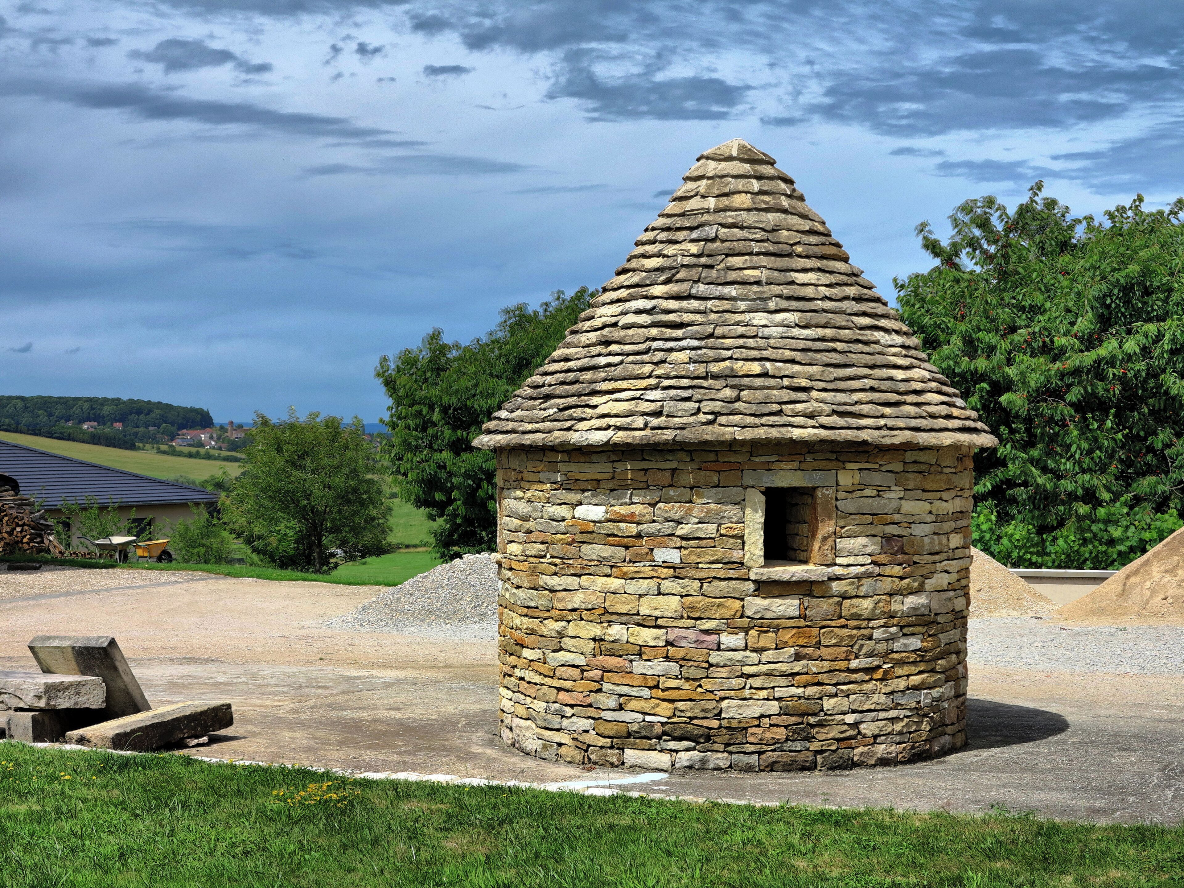 A stone tower with a conical roof in a rural setting.