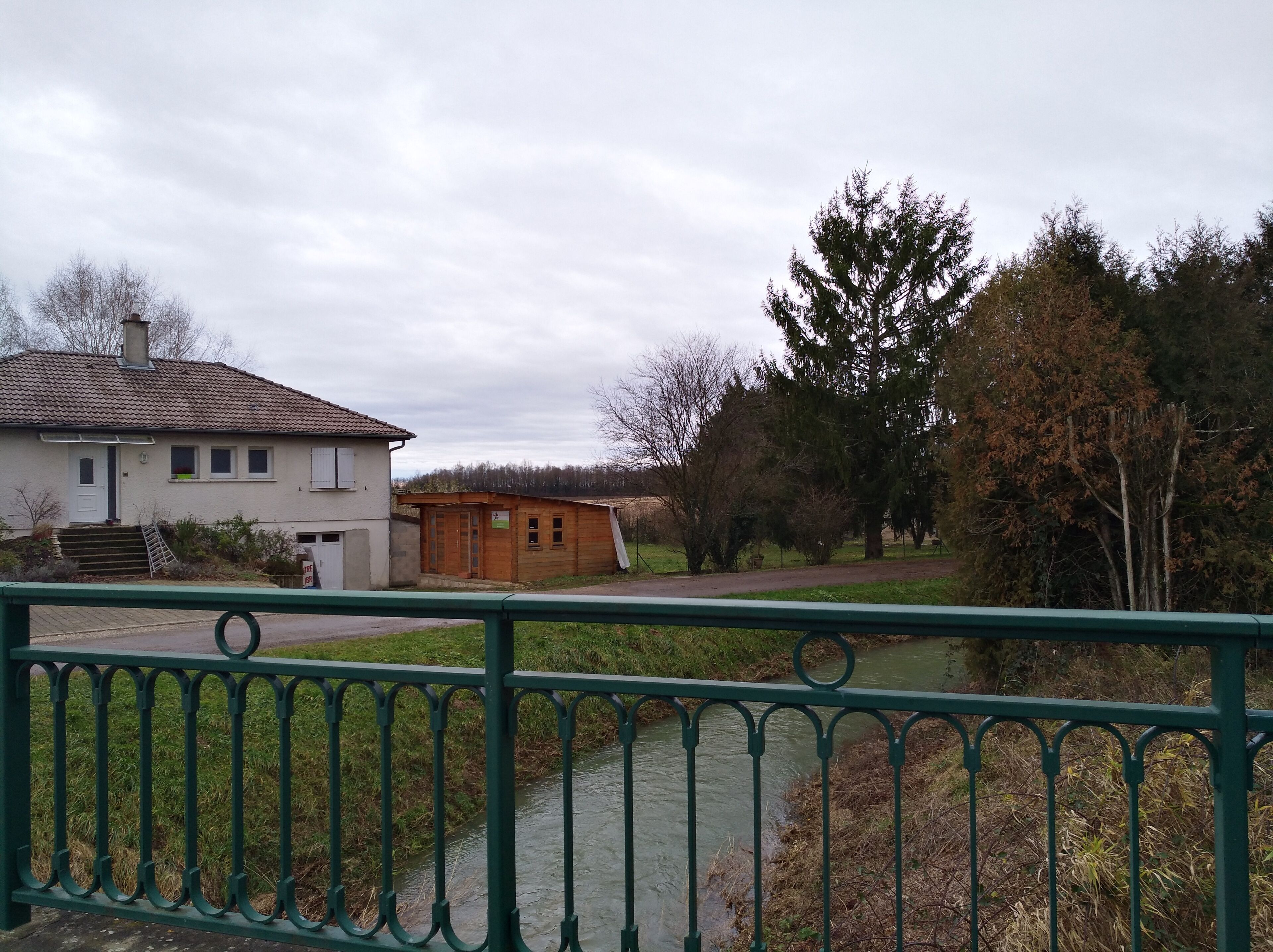 A house with a tiled roof, a wooden structure, and a river.