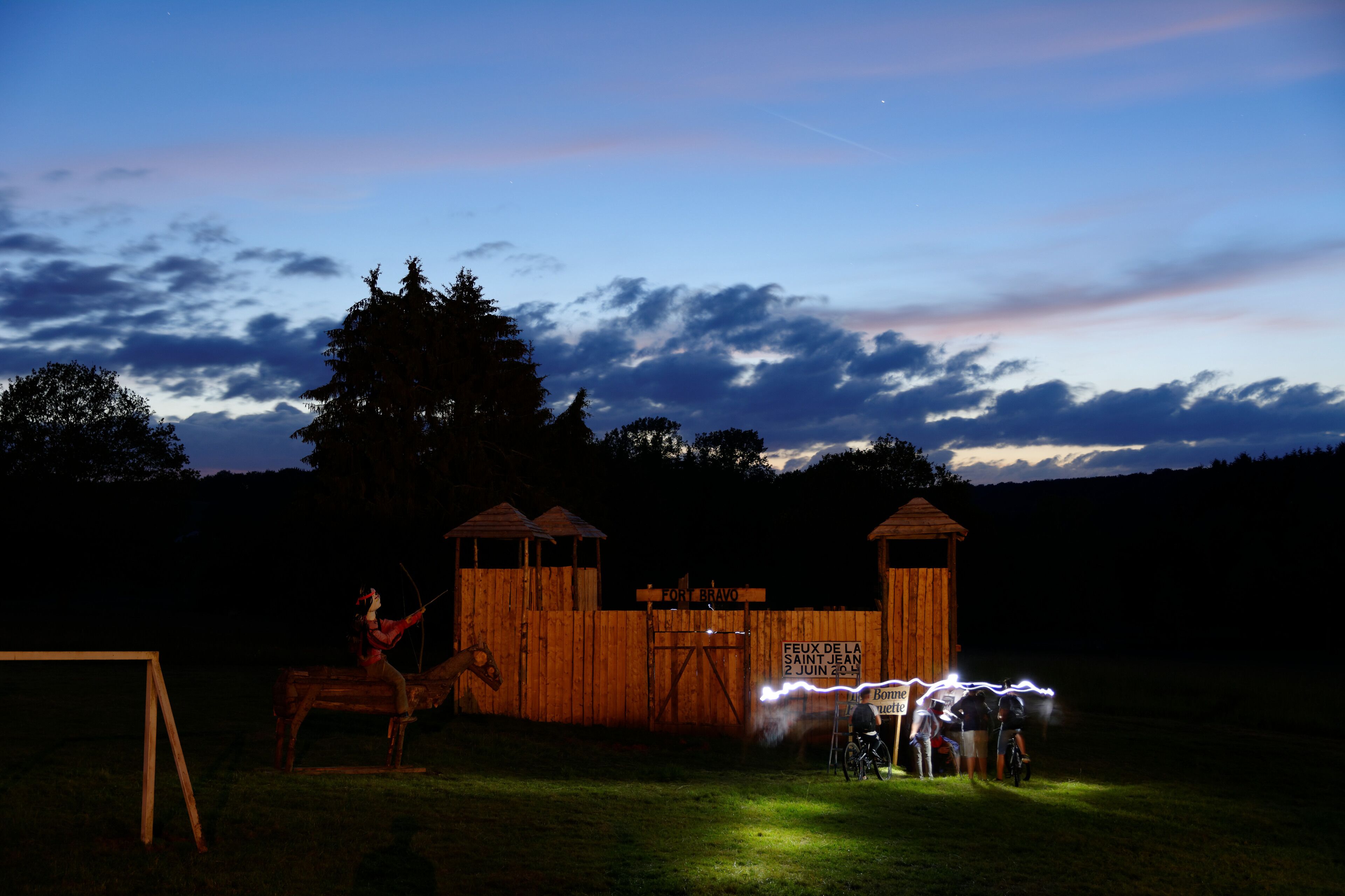 A wooden structure with two towers and a sign reading "FORT BRAVO" at dusk.