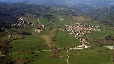 A rural landscape with rolling hills, a small village, and winding roads.