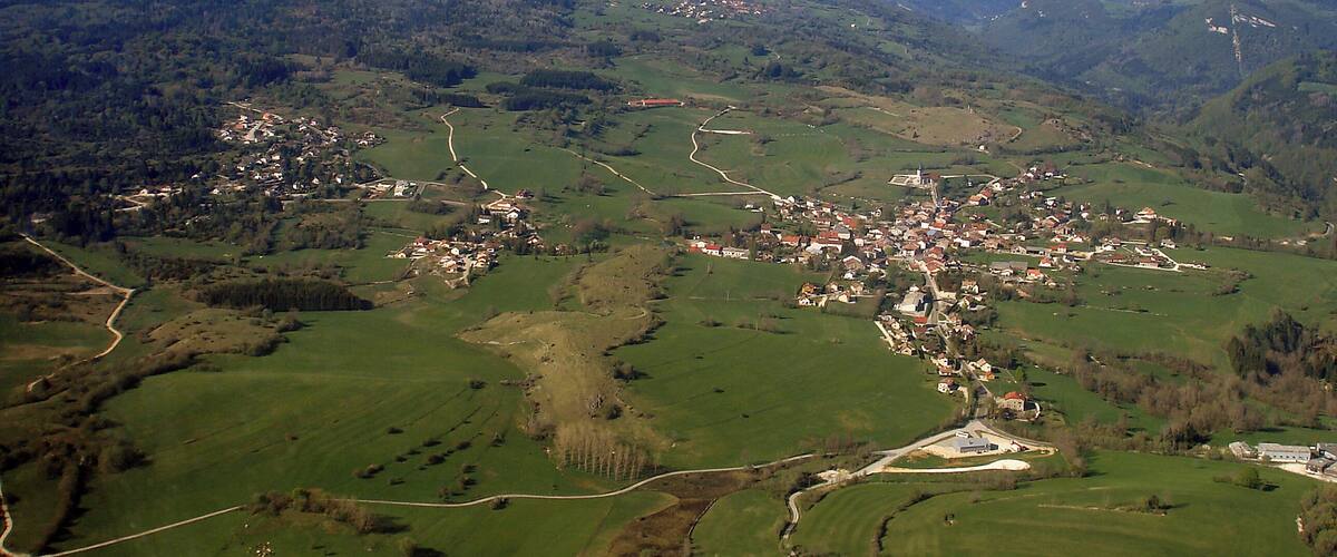 A rural landscape with rolling hills, a small village, and winding roads.
