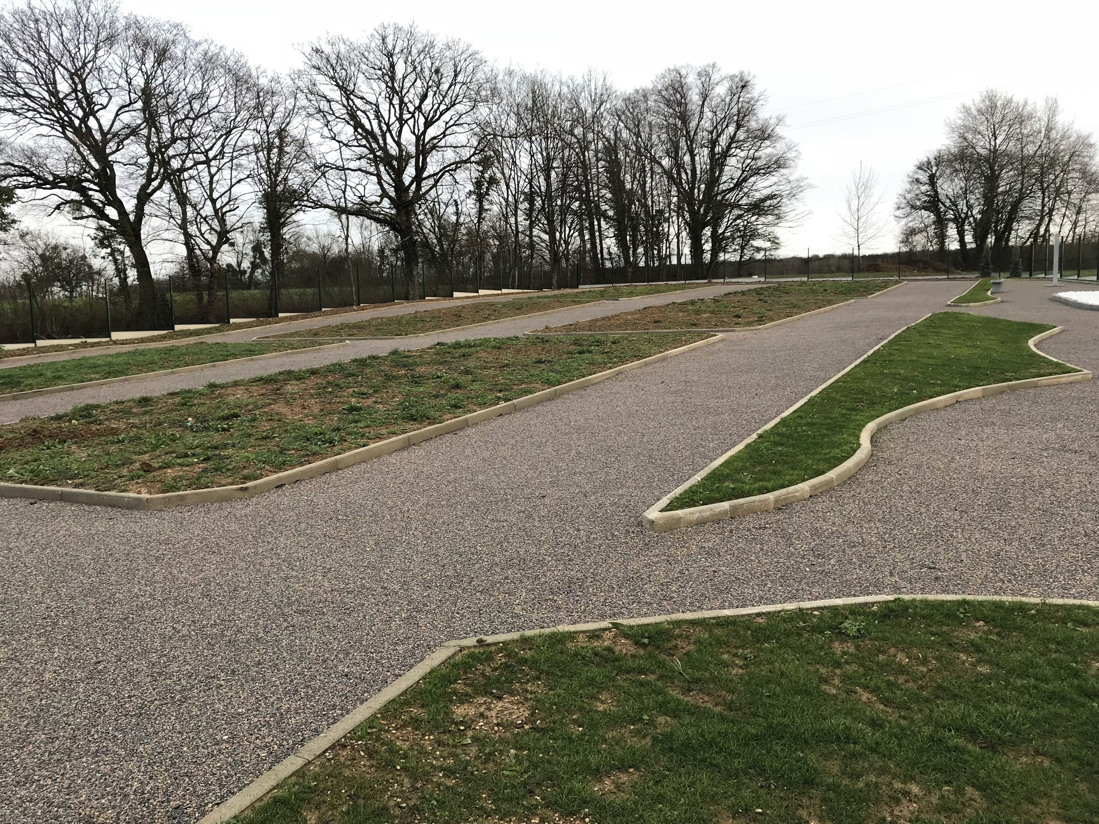 A park with gravel paths, green lawns, and leafless trees.