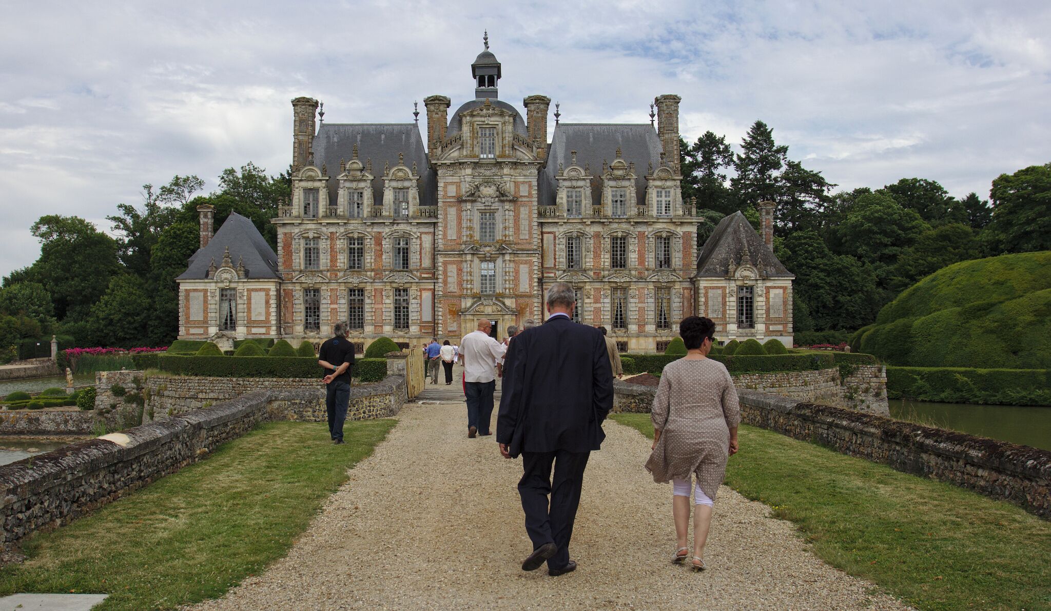 A grand château with a symmetrical facade, multiple chimneys, and a central dome.